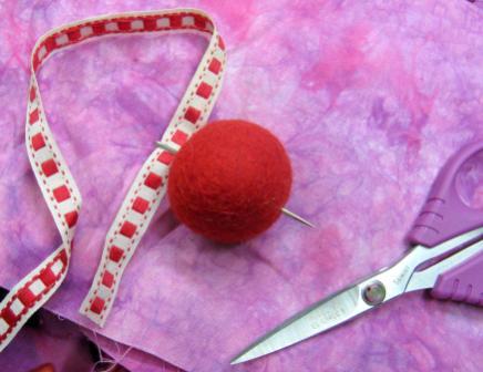 Thread the ribbon trim through the felt bead with the tapestry needle. Tie the ribbon trim in a knot.